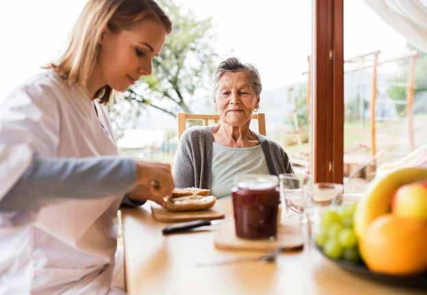 Carer preparing food with an older woman
